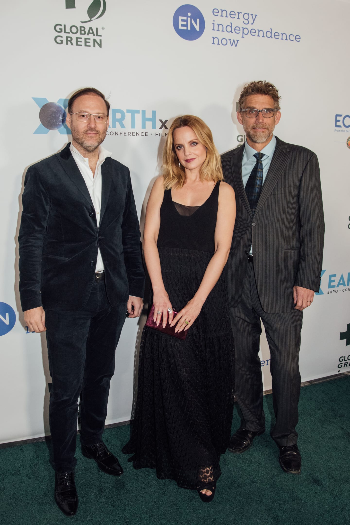 Actress Mena Suvari in black with two guests on the green carpet at the Global Green pre-Oscar gala