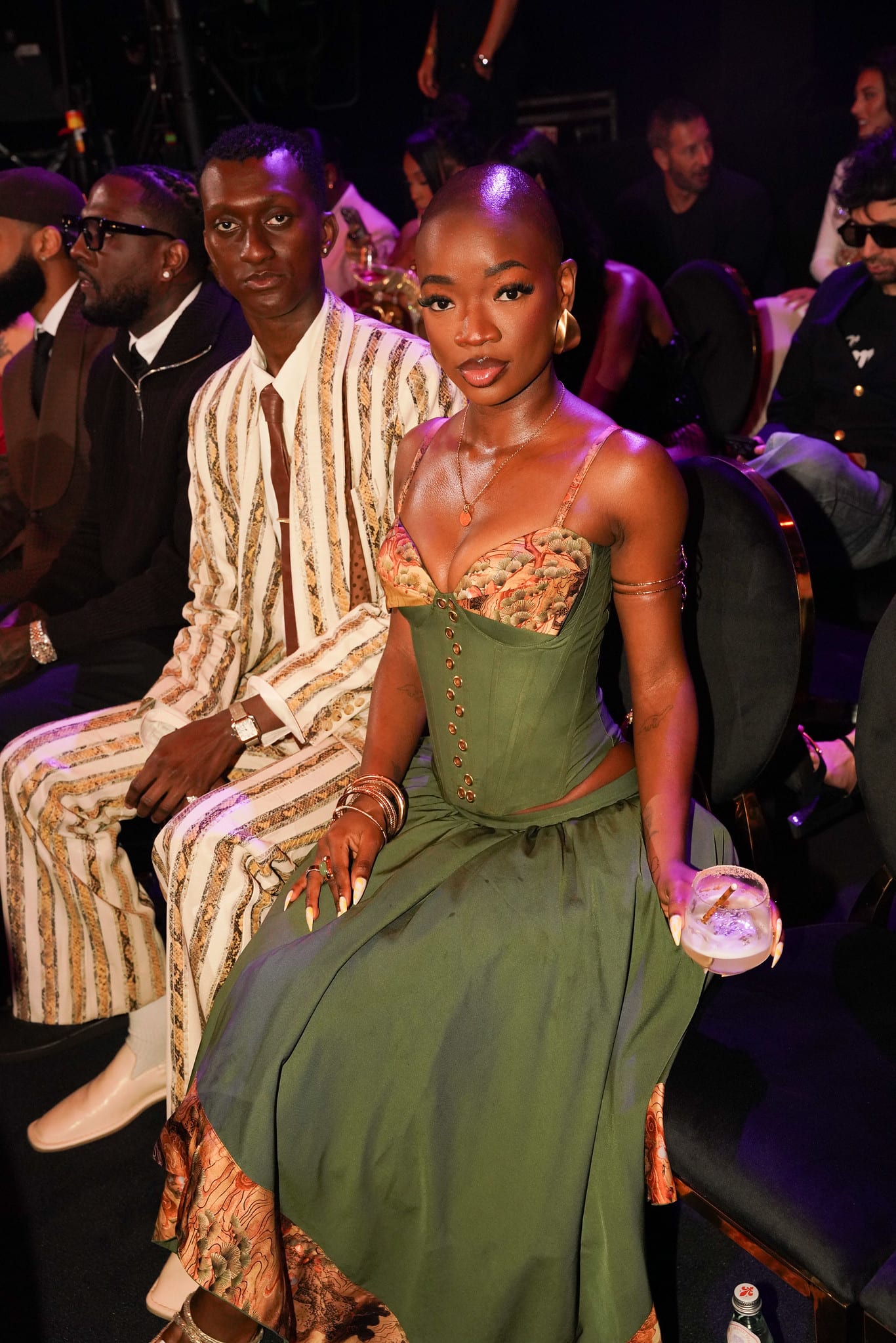 Two guests seated in the audience, one in a green gown