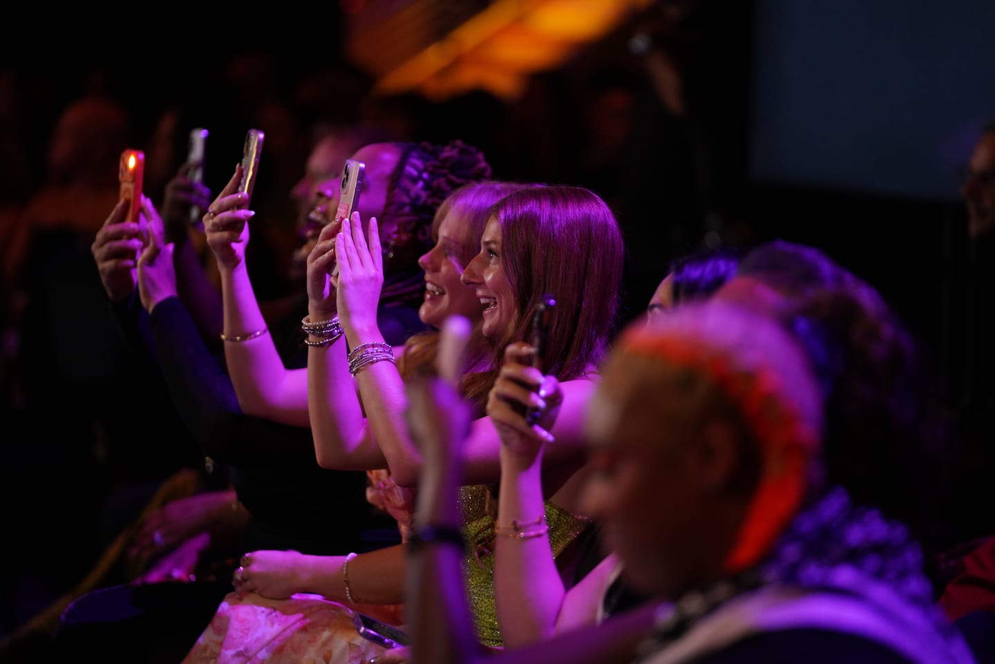 The audience holding phones up during the show in purple light