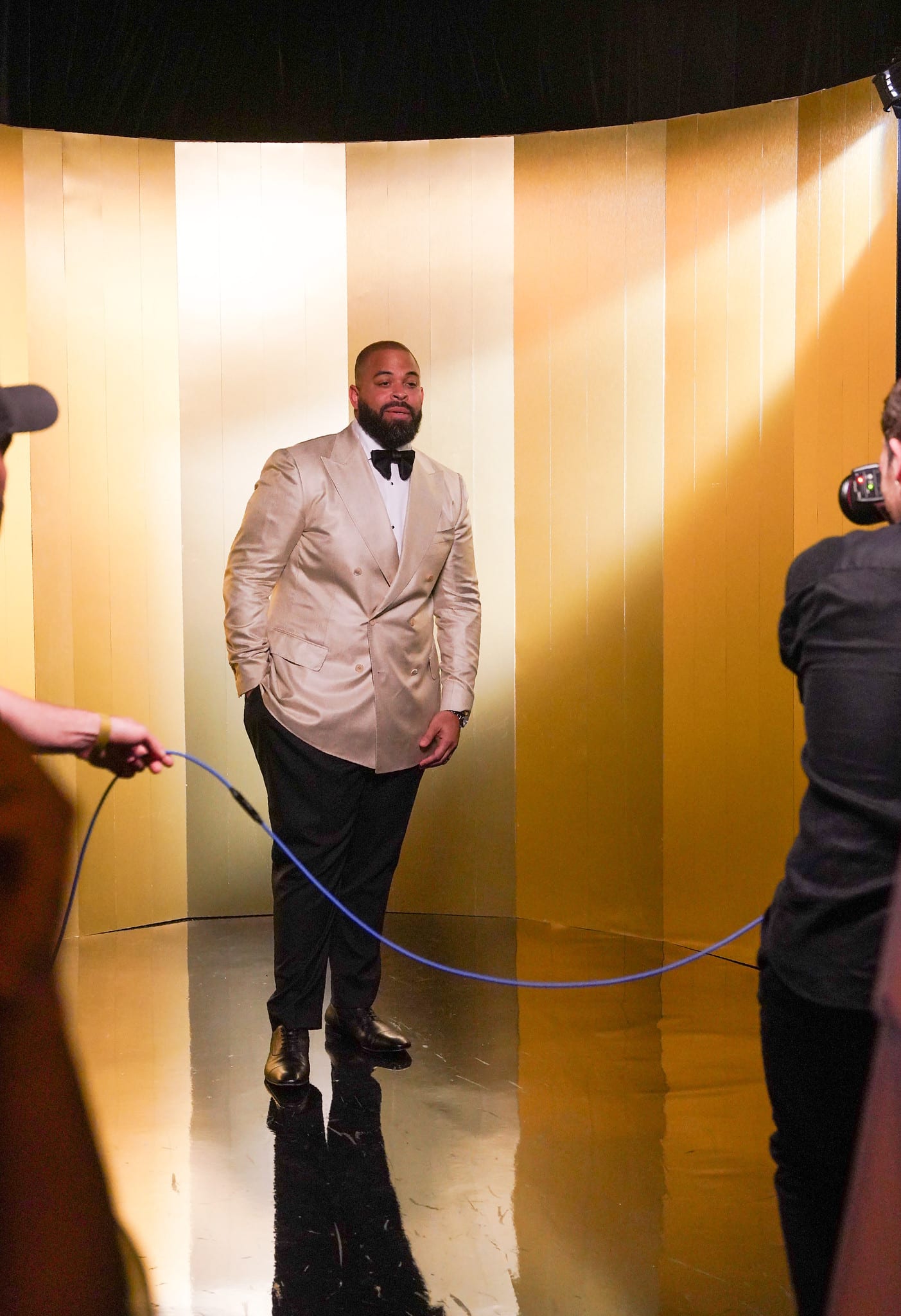 A host being fitted with a microphone in a gold-lit backstage corridor