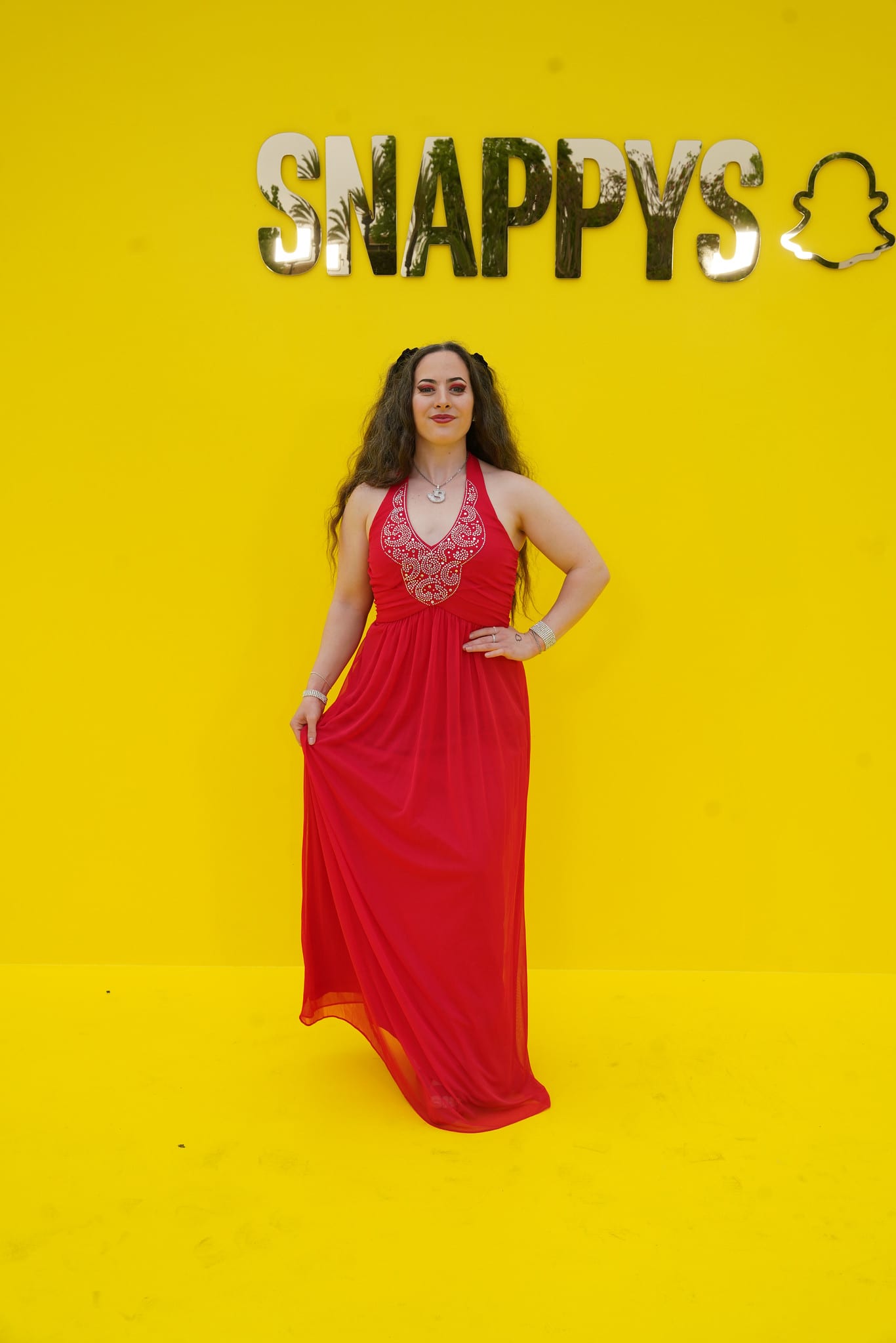 A guest in a red gown against the yellow SNAPPYS backdrop