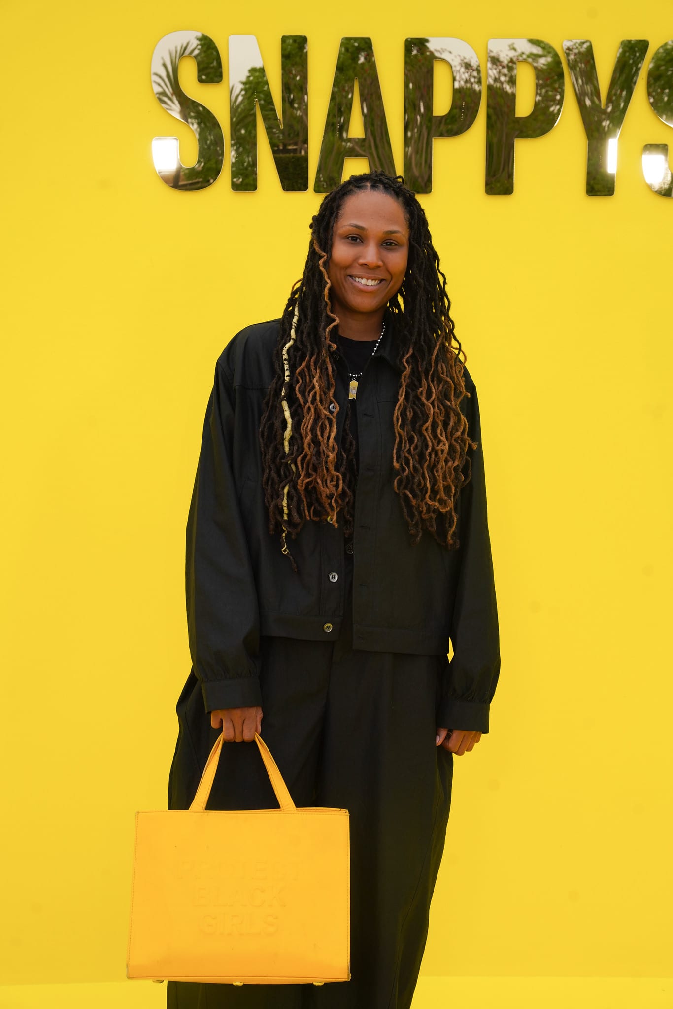A guest in black with a yellow bag against the SNAPPYS backdrop