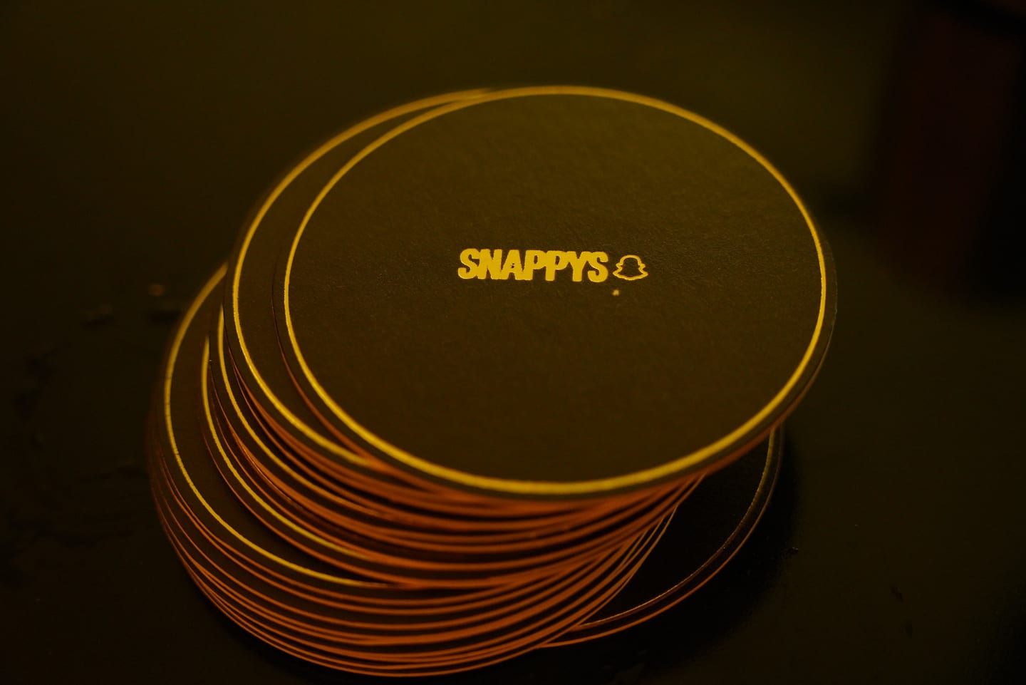 A stack of gold SNAPPYS coasters