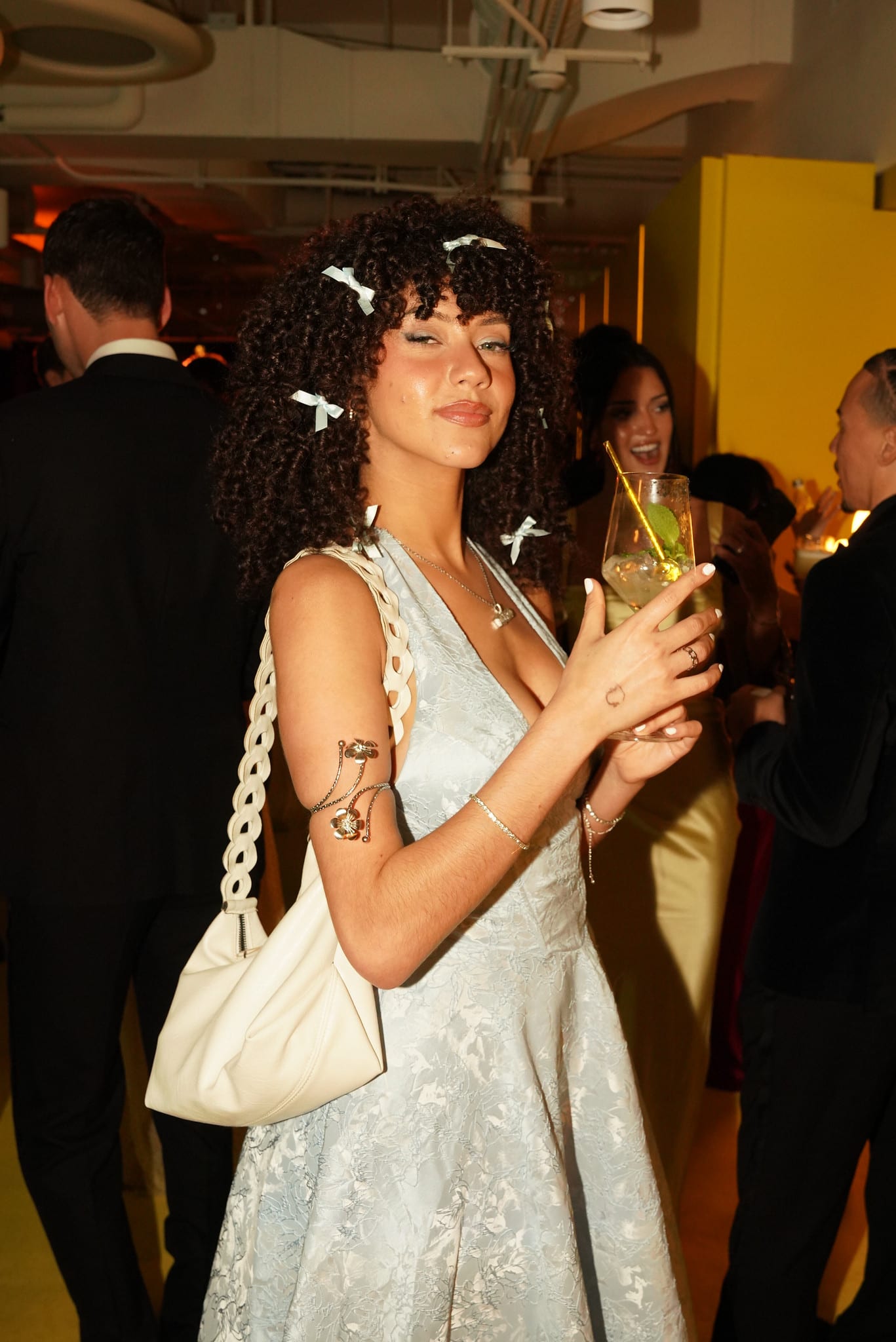 A guest in a white dress holding a drink at the reception
