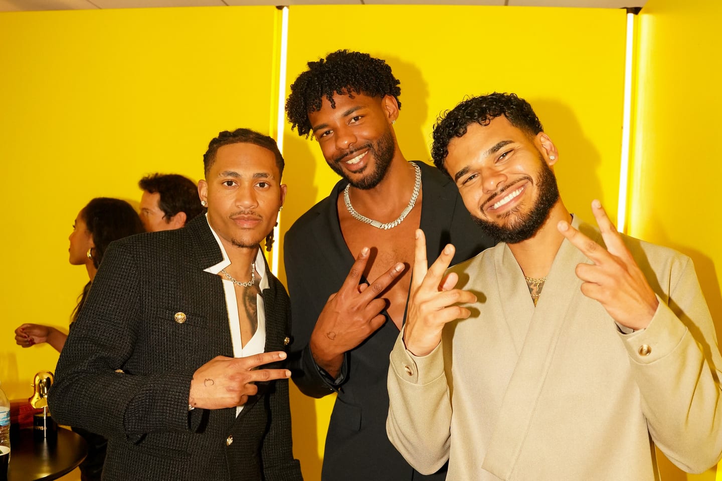 Three guests posing against a yellow wall