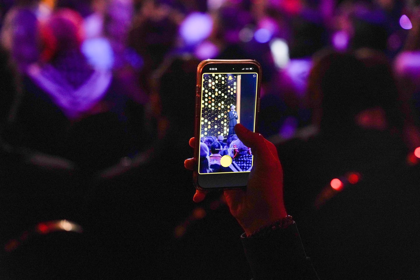 A phone held up filming the show above the crowd