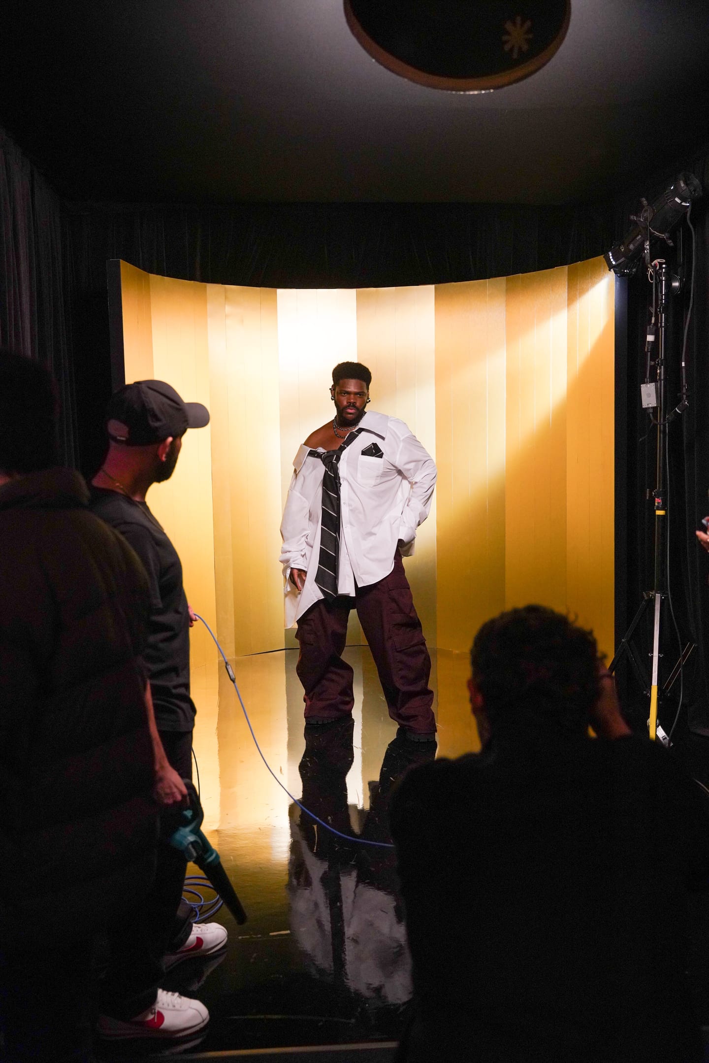 A creator being filmed on the gold set as crew work around him