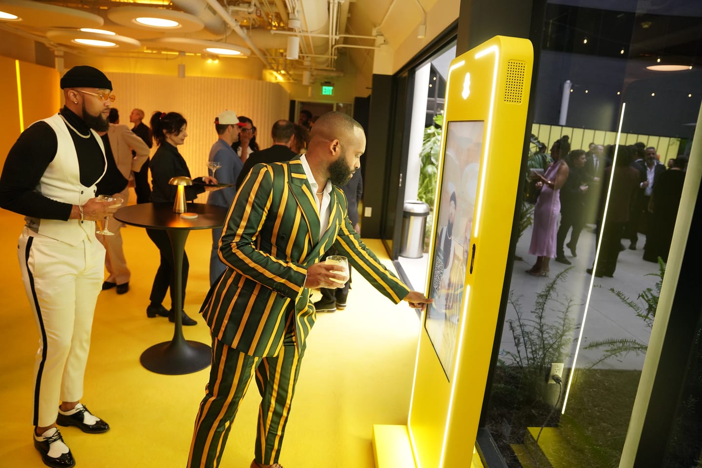 A guest in a green striped suit at a yellow interactive kiosk