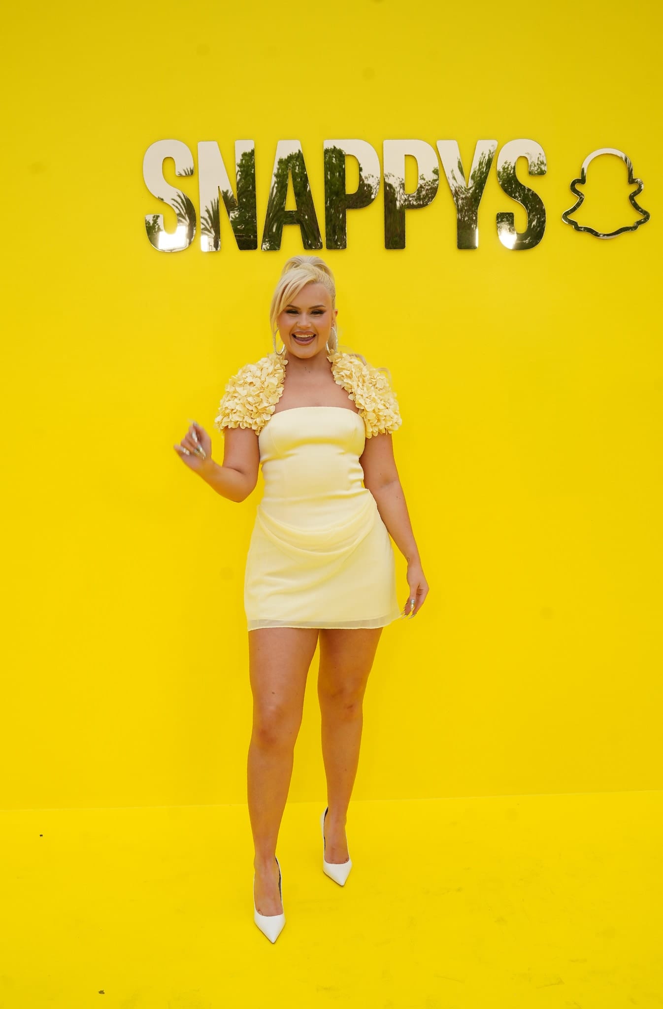 A guest in a yellow dress on the yellow carpet against the SNAPPYS backdrop at Snapchat’s creator awards in Santa Monica