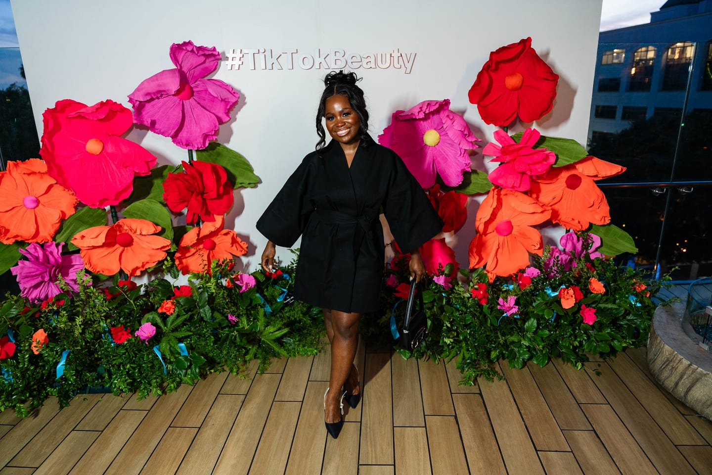 A guest in black walking the #TikTokBeauty floral step-and-repeat on the rooftop deck at the TikTok and Ulta Beauty #TikTokBeauty dinner on the LouLou rooftop in Santa Monica