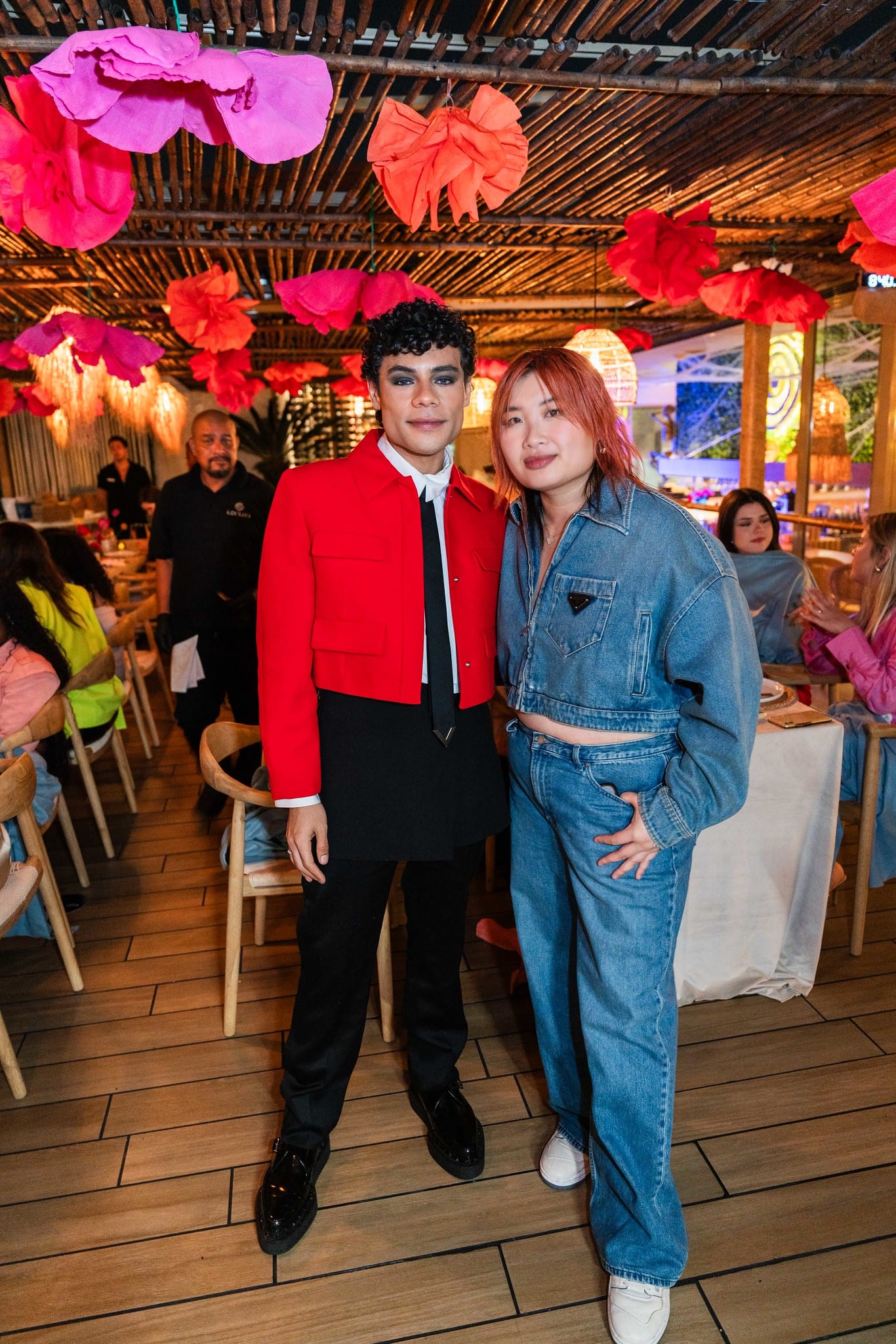 Two guests posing together on the rooftop under hanging paper flowers at the TikTok and Ulta Beauty #TikTokBeauty dinner on the LouLou rooftop in Santa Monica