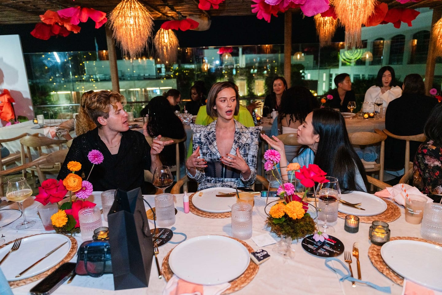 Guests seated at the long dinner table at night with string lights and an Ulta Beauty bag on the table at the TikTok and Ulta Beauty #TikTokBeauty dinner on the LouLou rooftop in Santa Monica