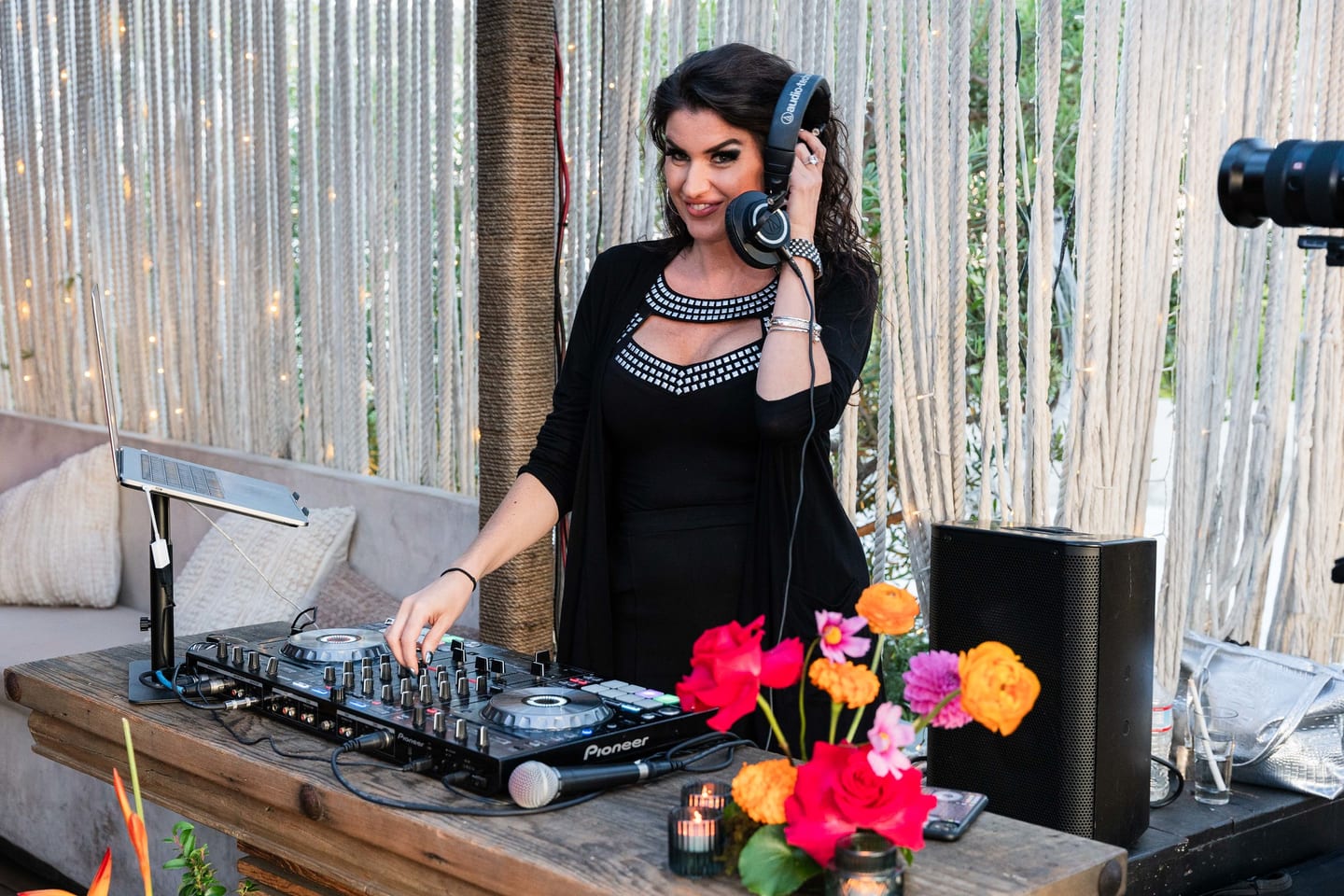 A DJ in headphones working the decks beside a bright floral arrangement at the TikTok and Ulta Beauty #TikTokBeauty dinner on the LouLou rooftop in Santa Monica