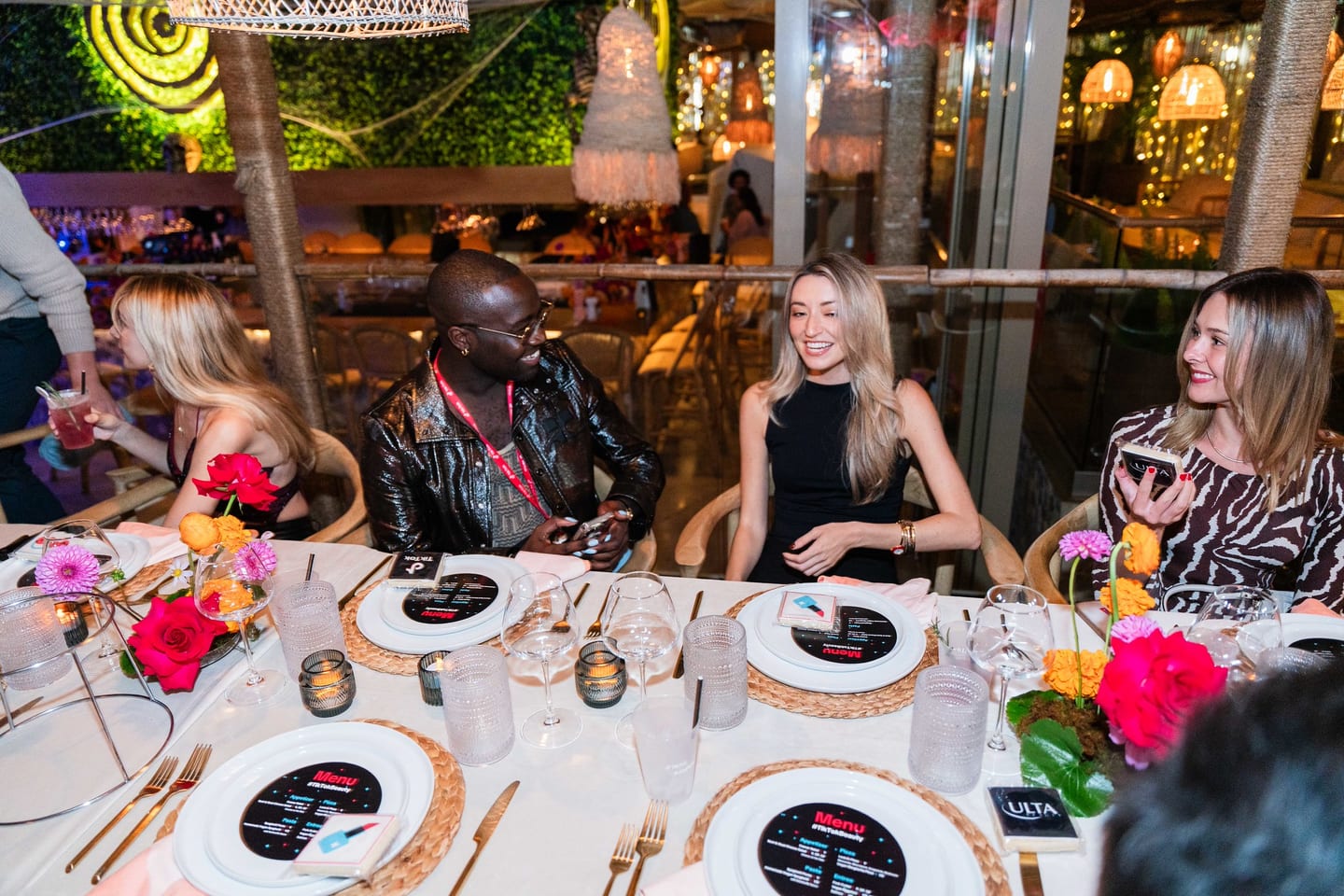 Four guests seated together at the dinner table smiling toward the camera at the TikTok and Ulta Beauty #TikTokBeauty dinner on the LouLou rooftop in Santa Monica