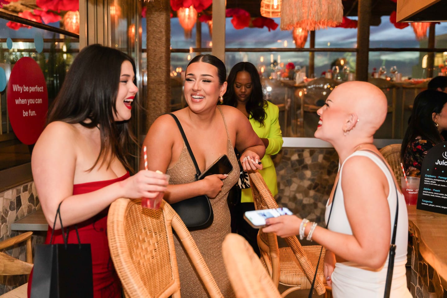 Three guests laughing together holding cocktails during the reception at the TikTok and Ulta Beauty #TikTokBeauty dinner on the LouLou rooftop in Santa Monica