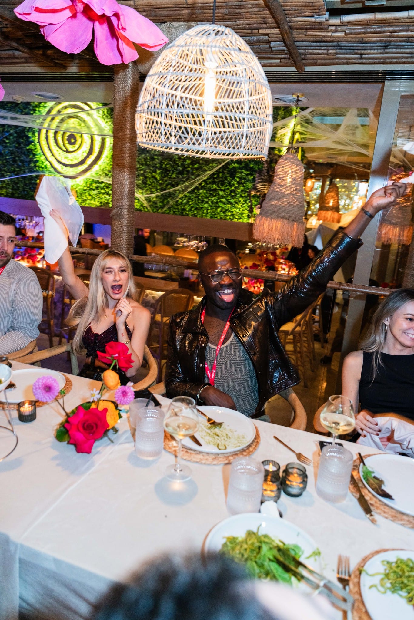 Guests seated at dinner beneath woven rattan pendant lights at the TikTok and Ulta Beauty #TikTokBeauty dinner on the LouLou rooftop in Santa Monica