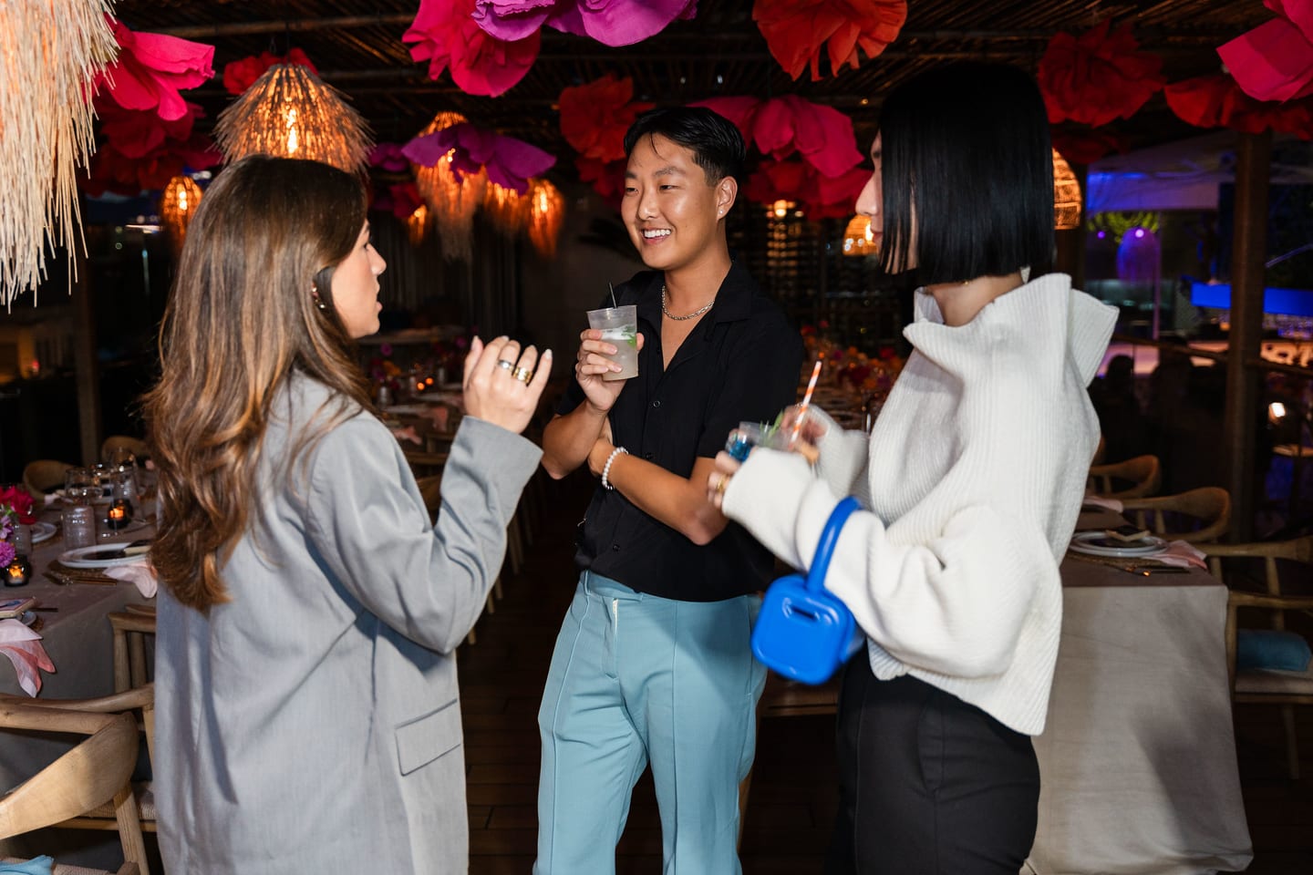 Three guests standing together with drinks in the rooftop dining room at the TikTok and Ulta Beauty #TikTokBeauty dinner on the LouLou rooftop in Santa Monica