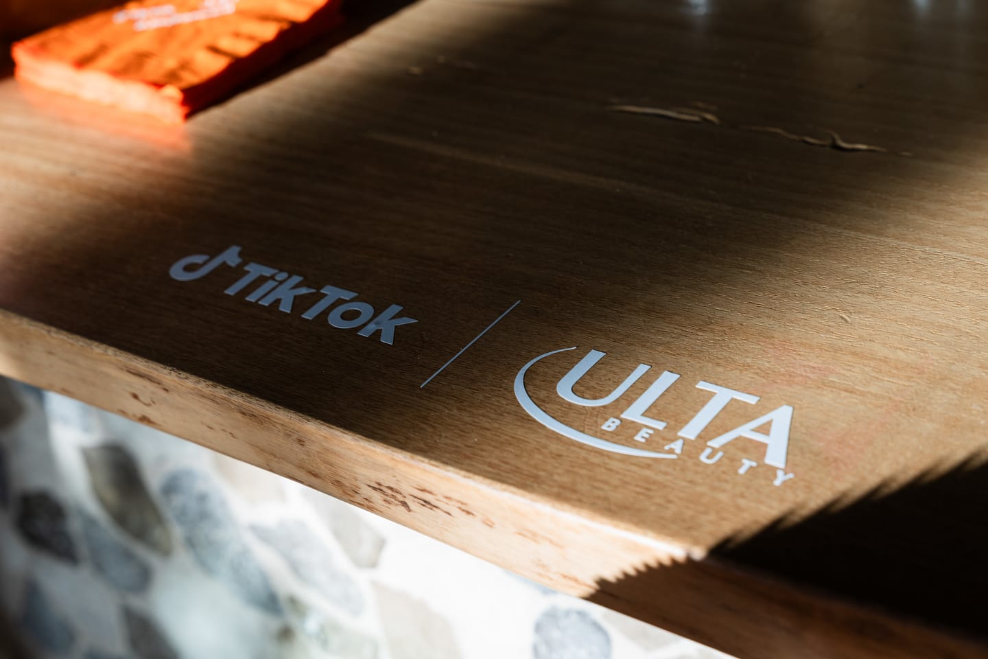 A TikTok and Ulta Beauty co-branded logo lockup projected on a wooden surface at the TikTok and Ulta Beauty #TikTokBeauty dinner on the LouLou rooftop in Santa Monica