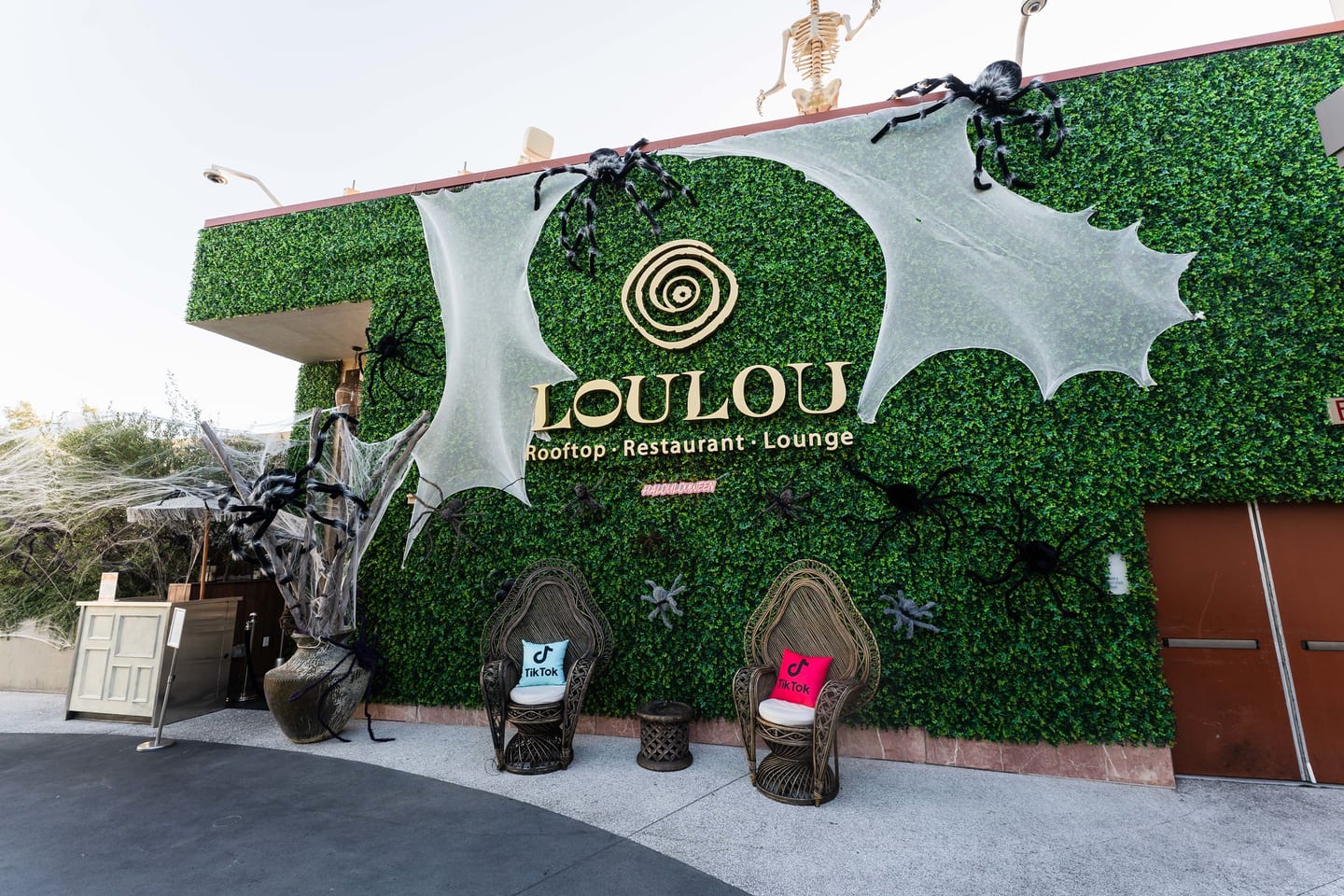 A wide view of the hedge-wall entrance to LouLou Rooftop in Santa Monica with the venue sign and Halloween decoration, before guests arrive for a TikTok and Ulta Beauty event