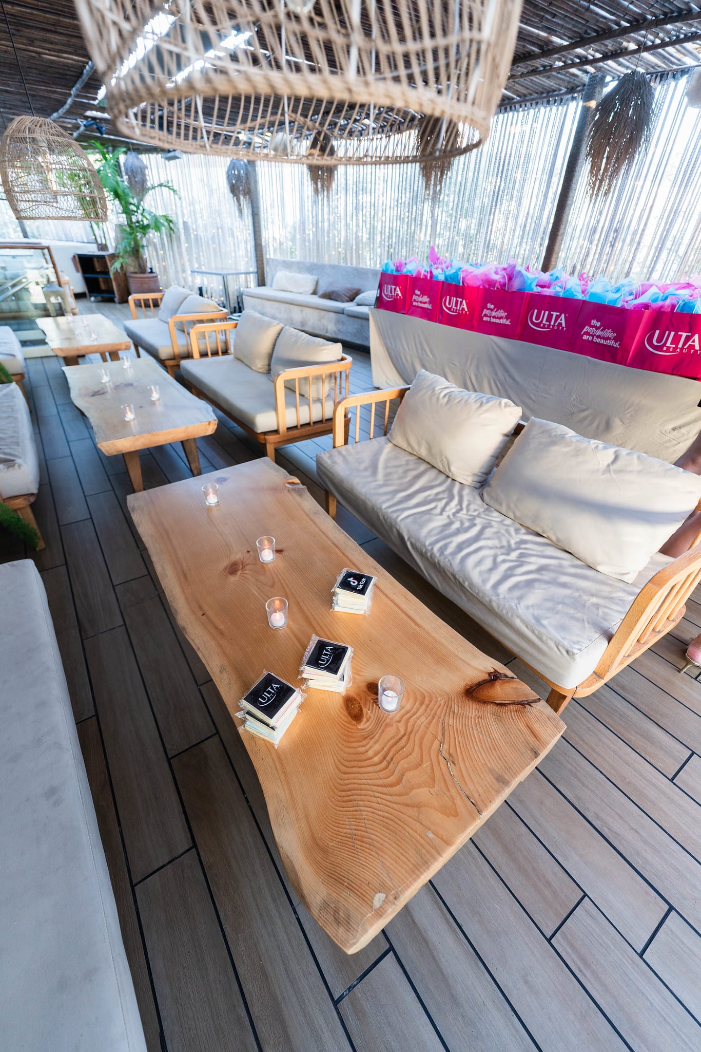 Rooftop lounge seating with pink Ulta Beauty gift bags set out on the tables at the TikTok and Ulta Beauty #TikTokBeauty dinner on the LouLou rooftop in Santa Monica