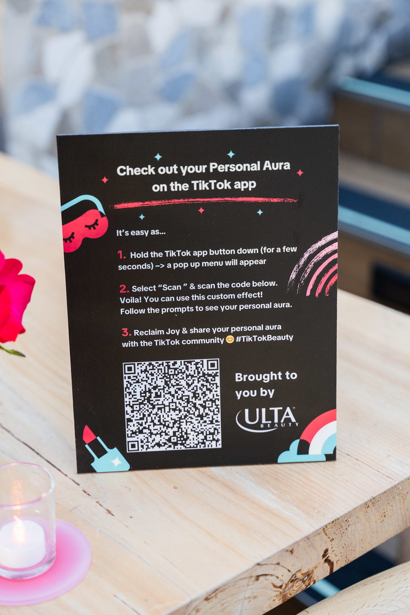 A printed card inviting guests to check their Personal Aura in the TikTok app, with a QR code and Ulta Beauty branding at the TikTok and Ulta Beauty #TikTokBeauty dinner on the LouLou rooftop in Santa Monica
