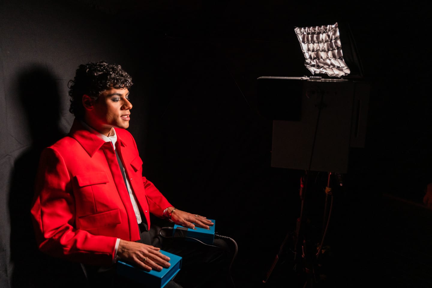 A guest in a red suit lit by a single spotlight late in the evening at the TikTok and Ulta Beauty #TikTokBeauty dinner on the LouLou rooftop in Santa Monica