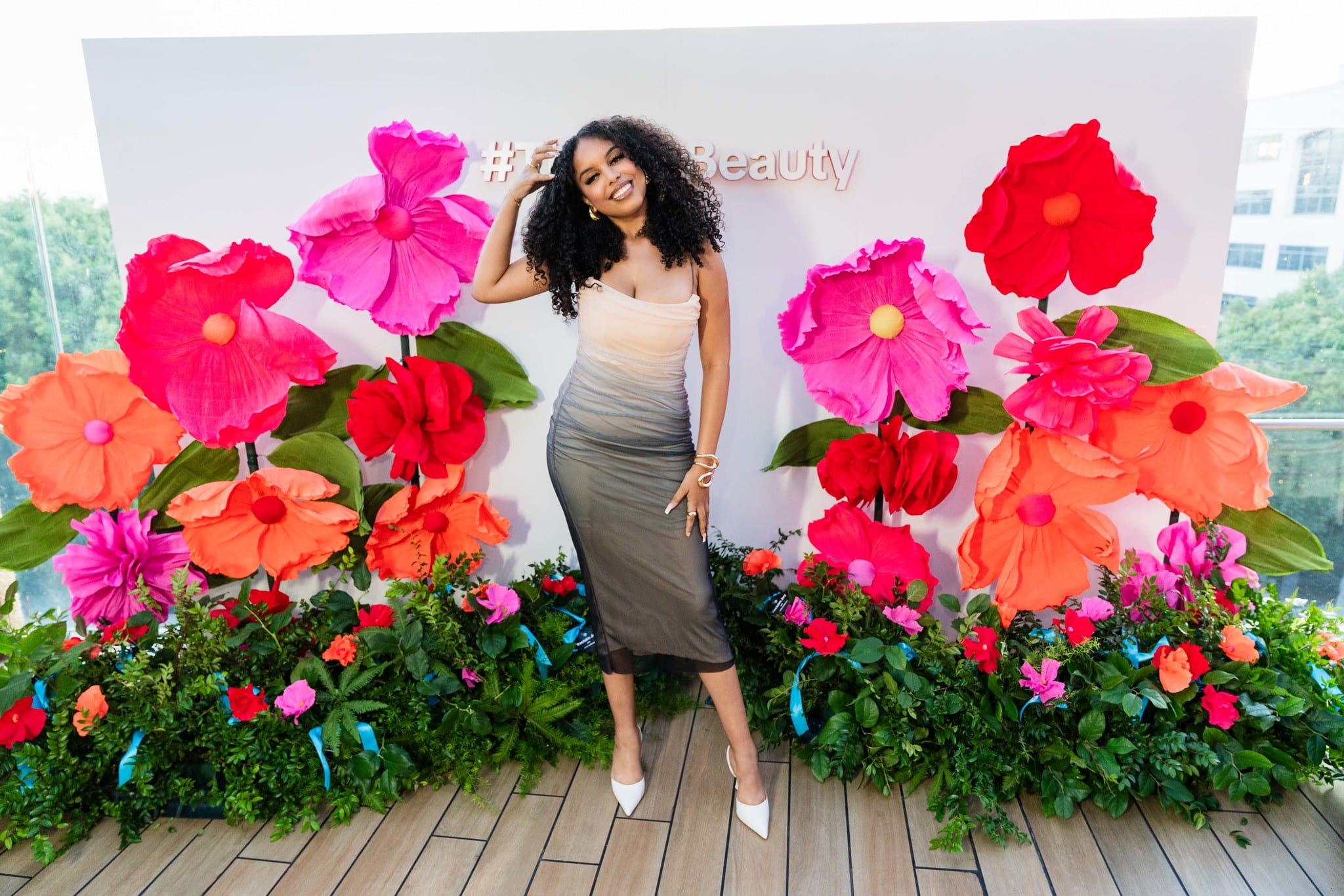 A guest posing among oversized pink, red, and orange flowers at a TikTok Beauty and Ulta Beauty brand activation in Santa Monica