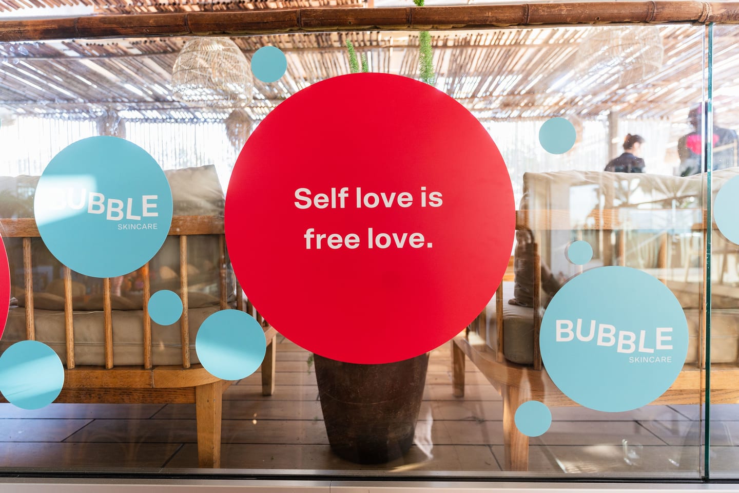 A large red window decal reading self love is free love, with teal Bubble circles, on the LouLou rooftop glazing at the TikTok and Ulta Beauty #TikTokBeauty dinner on the LouLou rooftop in Santa Monica