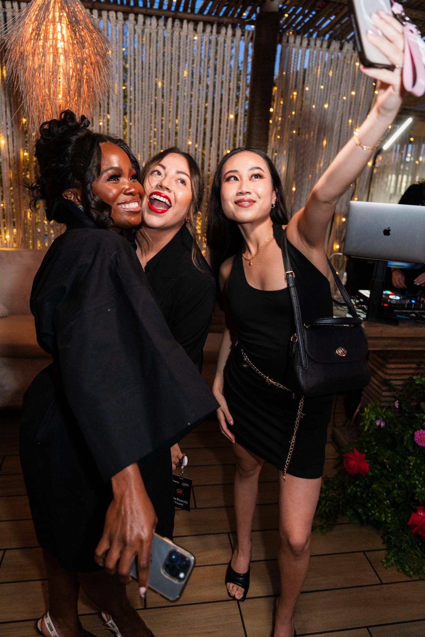 Three guests leaning in for a selfie under string lights on the rooftop at the TikTok and Ulta Beauty #TikTokBeauty dinner on the LouLou rooftop in Santa Monica