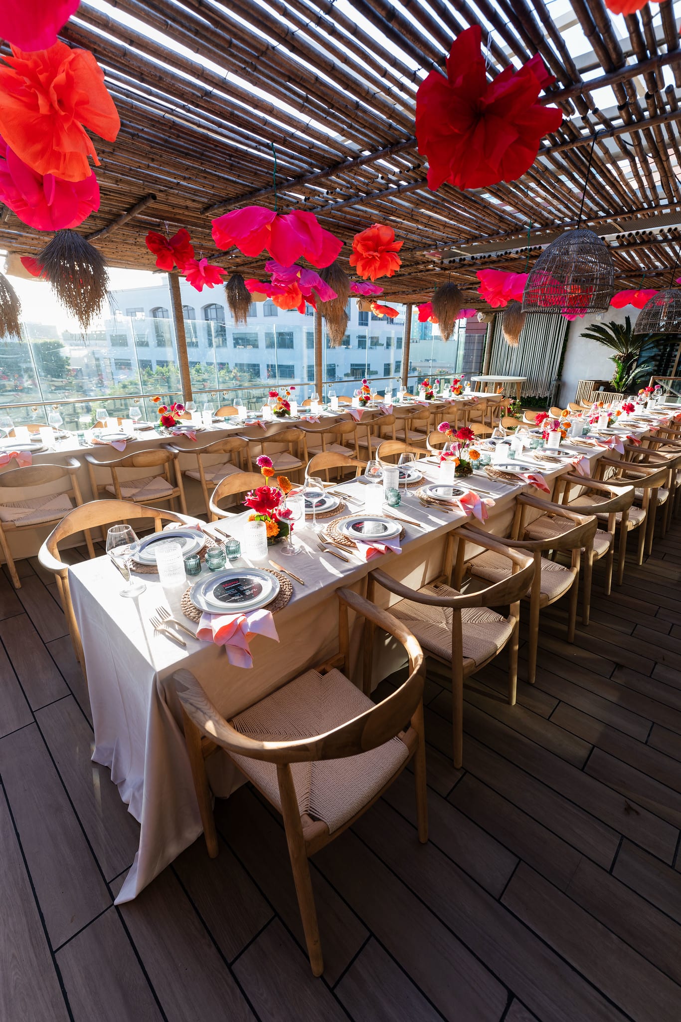 A wide view of the full length of the set dining table under paper flowers on the LouLou rooftop at the TikTok and Ulta Beauty #TikTokBeauty dinner on the LouLou rooftop in Santa Monica
