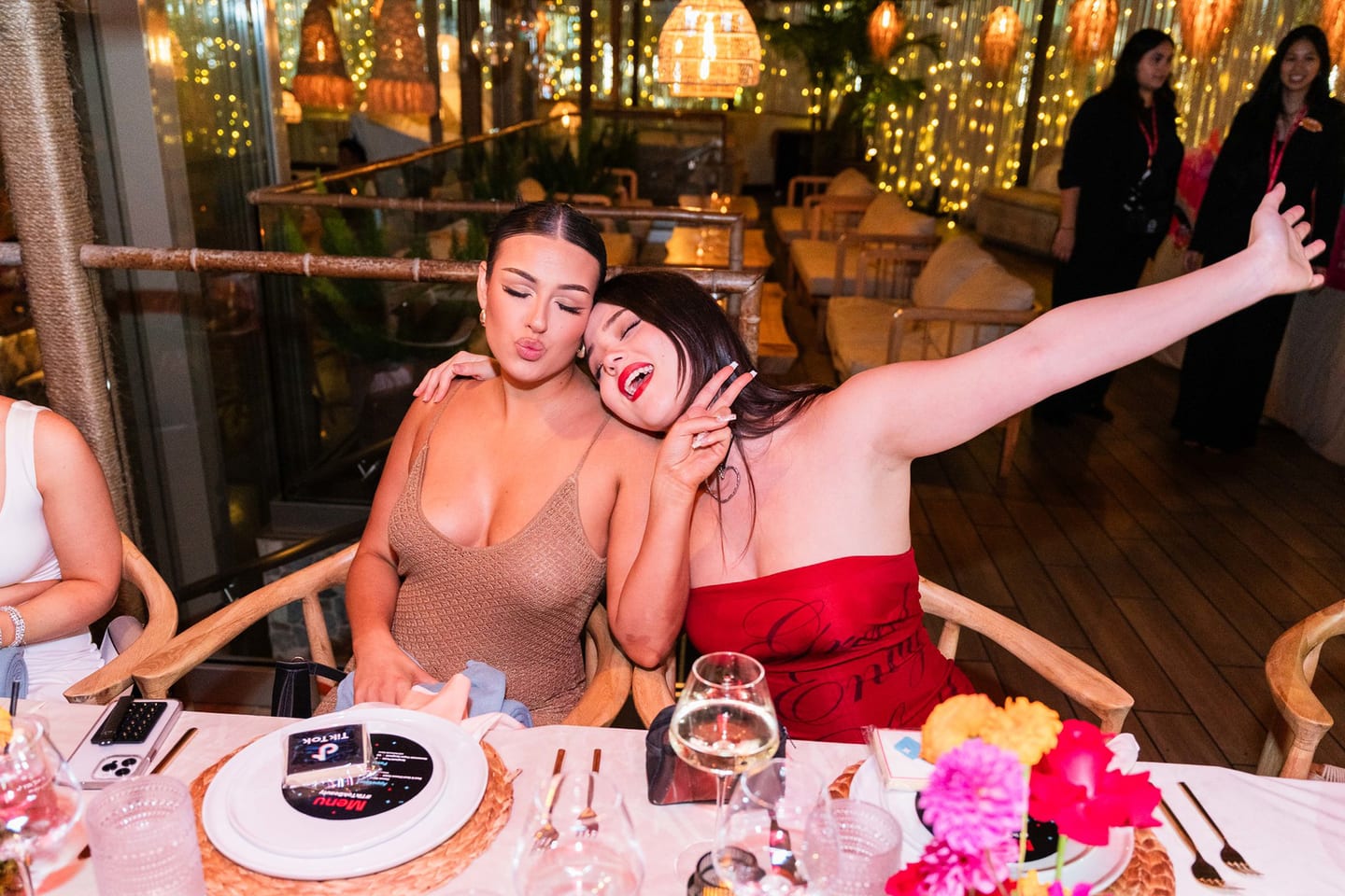 Three guests being playful at the dinner table, one with an arm outstretched at the TikTok and Ulta Beauty #TikTokBeauty dinner on the LouLou rooftop in Santa Monica