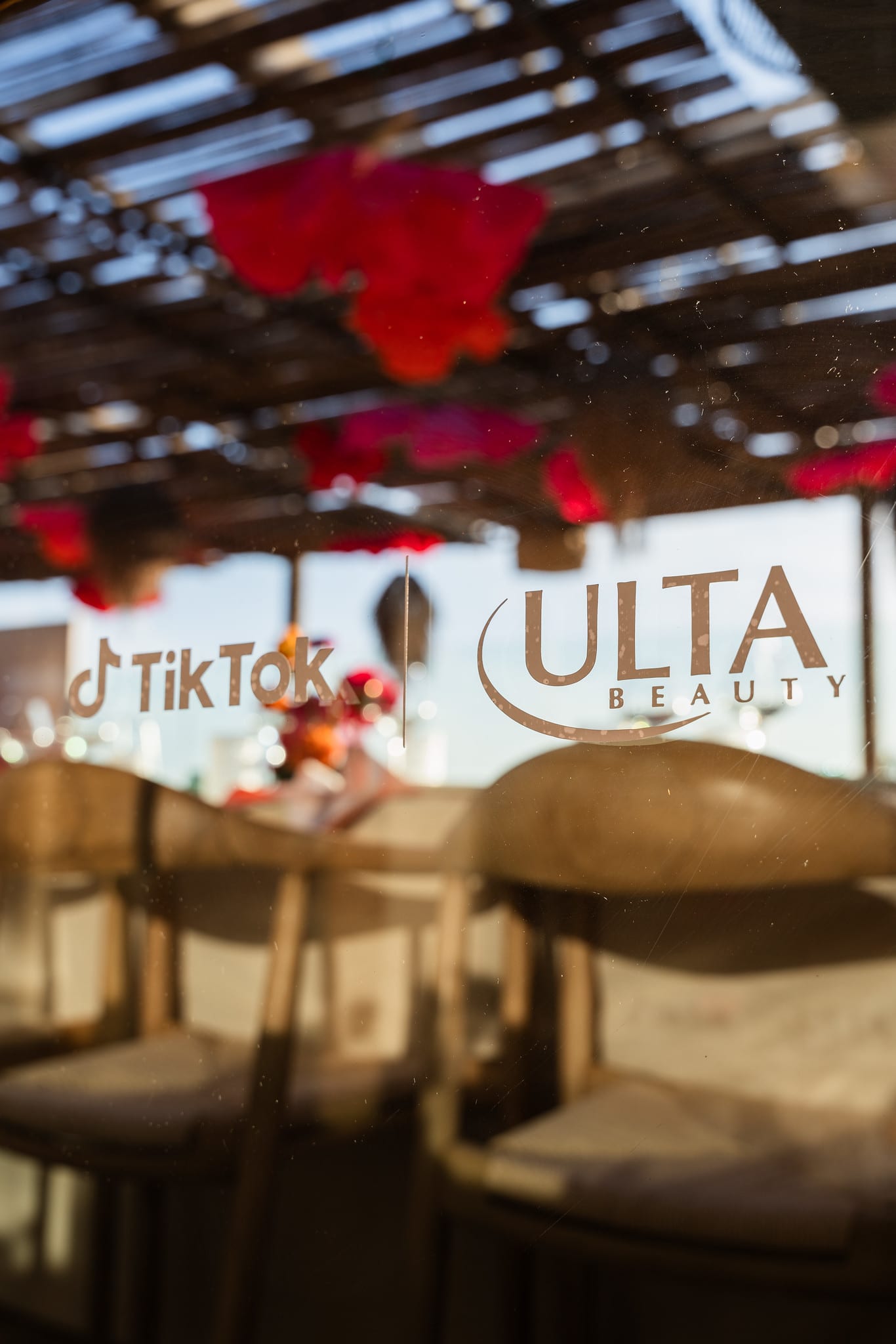 TikTok and Ulta Beauty logos applied to a glass rooftop panel with greenery behind at the TikTok and Ulta Beauty #TikTokBeauty dinner on the LouLou rooftop in Santa Monica