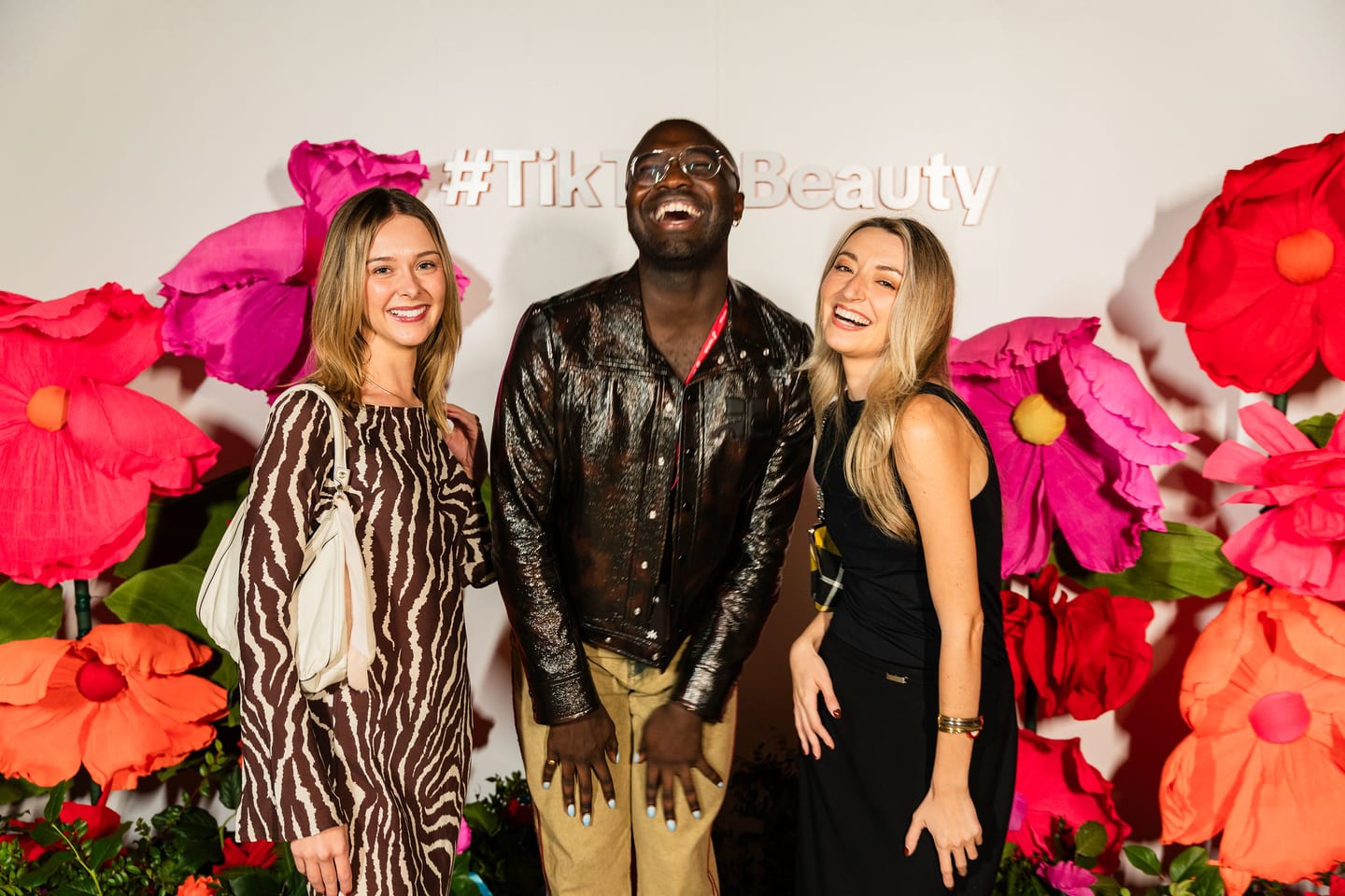 Three guests posing together at the oversized floral #TikTokBeauty backdrop at the TikTok and Ulta Beauty #TikTokBeauty dinner on the LouLou rooftop in Santa Monica