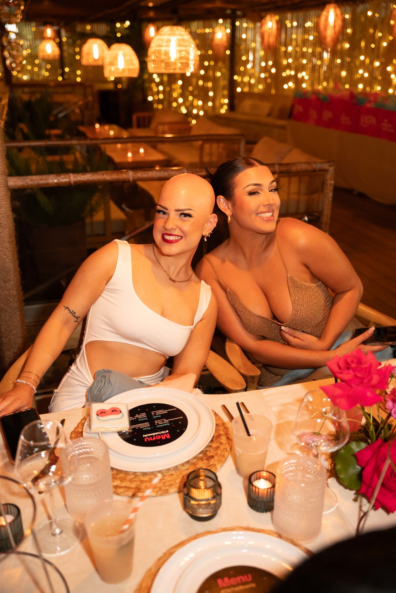 Two guests posing together at the dinner table at the TikTok and Ulta Beauty #TikTokBeauty dinner on the LouLou rooftop in Santa Monica