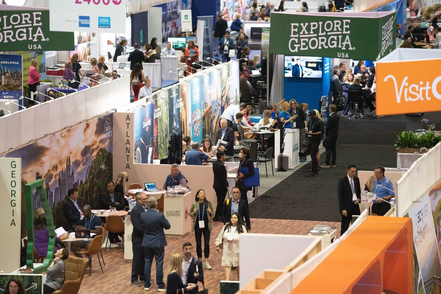 Busy trade-show floor with destination-marketing booths and attendees at a travel-industry expo
